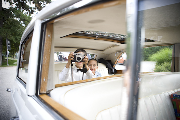 kids sitting in the car taking pictures of the bride and groom- wedding photo by top Canadian wedding photographer Rebecca Wood